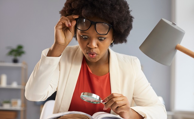 surprisedinquisitiveblackwomanwithmagnifyingglasstakesoffglasses