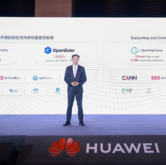 A man in a suit stands on stage with a prominent Huawei logo and large screen behind him. The display highlights information about Huawei's OpenEuler and OpenHarmony projects, listing supporting companies and contributors, with their logos shown in two rows.